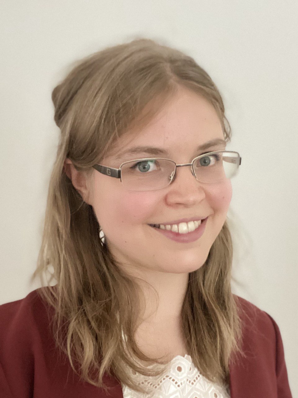 2026 Katharina Tartler Das farbige Foto zeigt die Kandidatin für den Pfarrgemeinderat St. Korbinian Katharina Tartler. Sie trägt eine Brille, eine weiße Bluse und ein weinrotes Jacket, sie hat dunkelblonde lange Haare