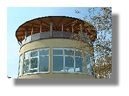 Kinderhort St. Korbinian Das farbige Foto zeigt das Gebäude des Kinderhort St. Korbinian von außen. Ein gelber Turm mit vielen Fenstern sowie einen Dach aus Holz